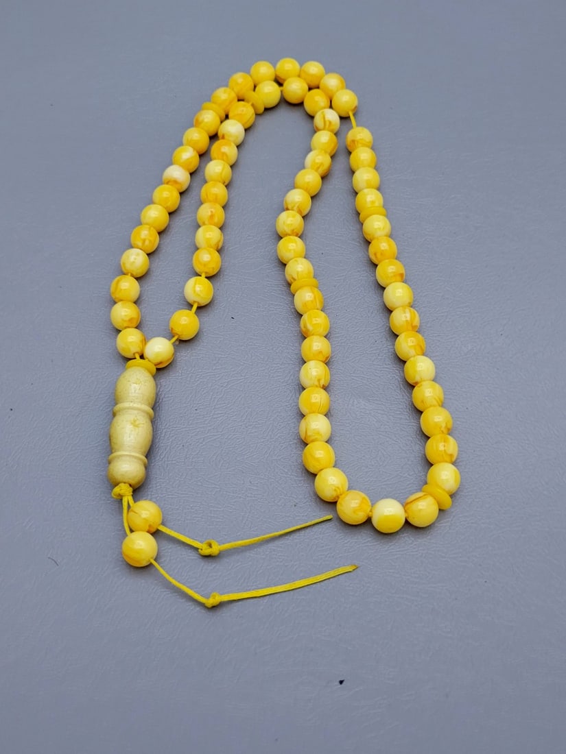 Vintage Islamic Natural Amber Beaded Misbaha: Vintage Islamic Natural Amber Beaded Misbaha in an egg yolk shade, composed of 65 round beads laced on a yellow fabric thread, total weight: 28 grams, total weight: 40 cm, diameter of each bead: 8 mm.