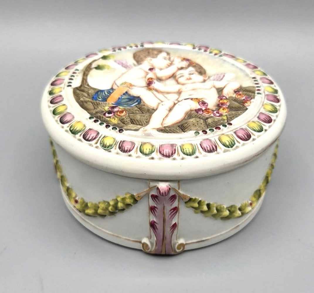 Quality antique porcelain box made by Capodimonte: High quality antique porcelain box made by Capodimonte, Italy, circa 1900, decorated with reliefs and hand painting in the pattern of two angels and plant decorations, signed on the bottom, diameter: