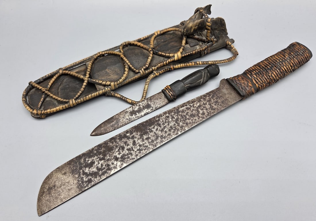 Old "bounty hunter" machete sword: An old "bounty hunter" machete sword, probably the Philippines, 20th century, steel blade, wooden handle covered with straw plaiting, wooden scabbard with straw plaiting decorations and part of a rode