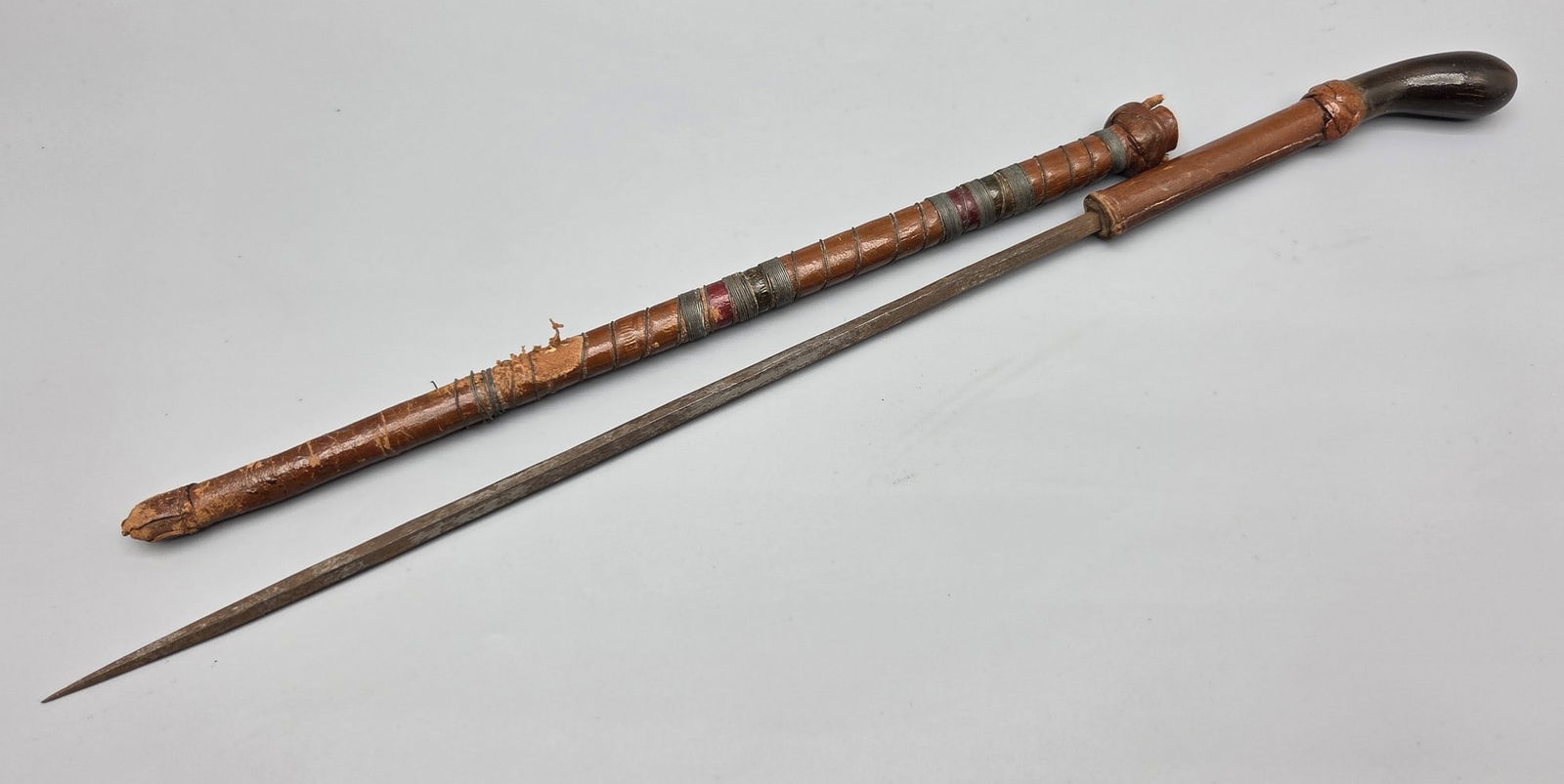 Antique leather officer's cane: An old "bounty hunter" machete sword, probably the Philippines, 20th century, steel blade, wooden handle covered with straw plaiting, wooden scabbard with straw plaiting decorations and part of a rode