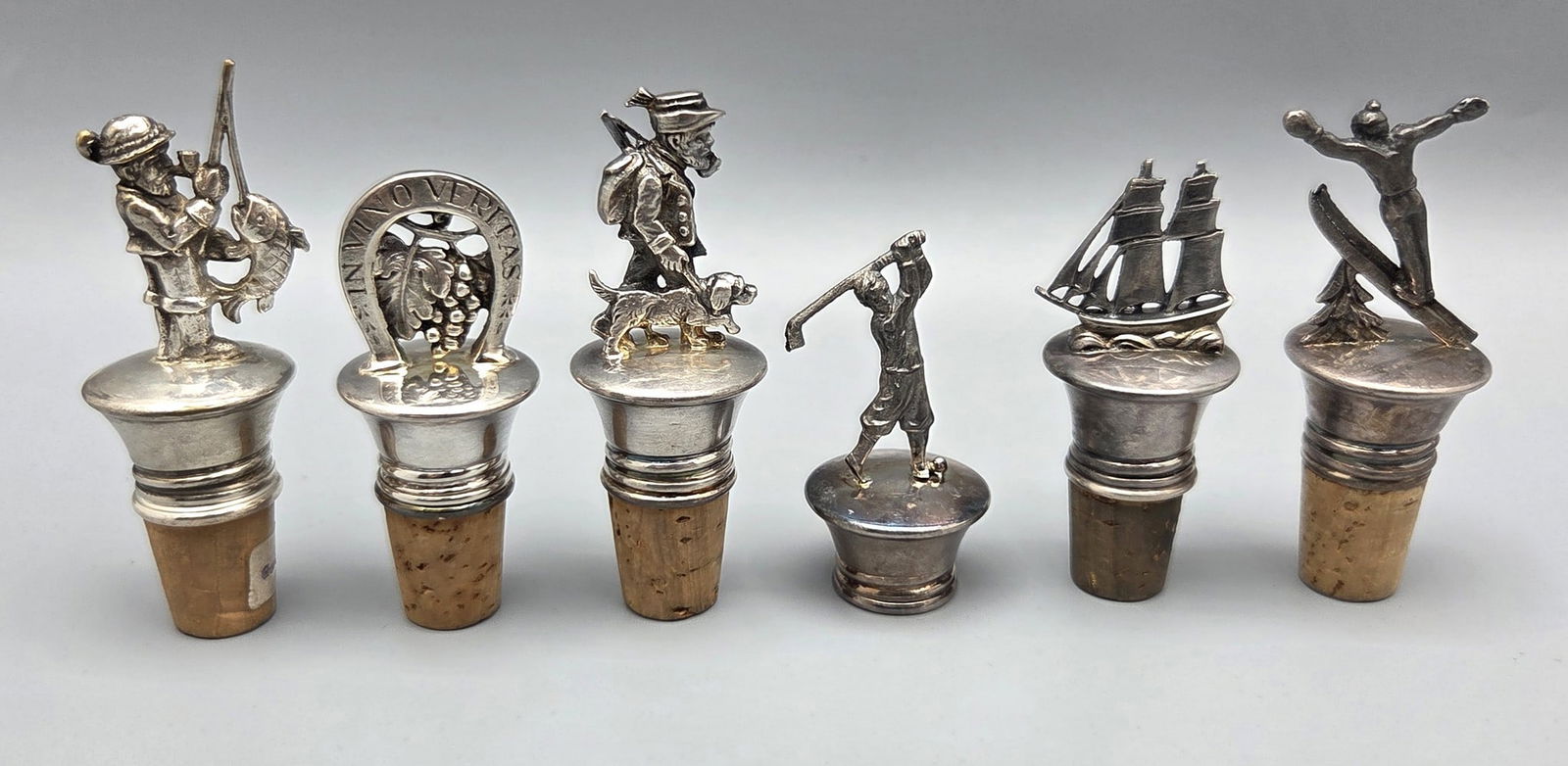 Assortment 6 cork stoppers for old silver-plated German bottles: Assortment 6 stoppers for old German bottles, 20th century, made of silver-plated metal, designed with different models on the heads: a skier, a fisherman, a golfer, the hunter and his dog, a ship and