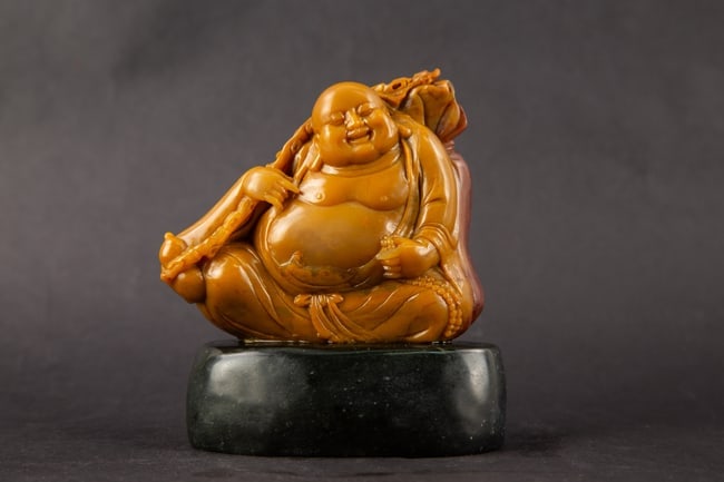 Carved Hardstone Laughing Buddha Figure: Title: Carved Hardstone Laughing Buddha Figure Medium: Carved Hardstone Size: 4." H x 1.5" W x 5." L Condition: Good vintage condition with wear consistent with age and use. Minor surface wear and age