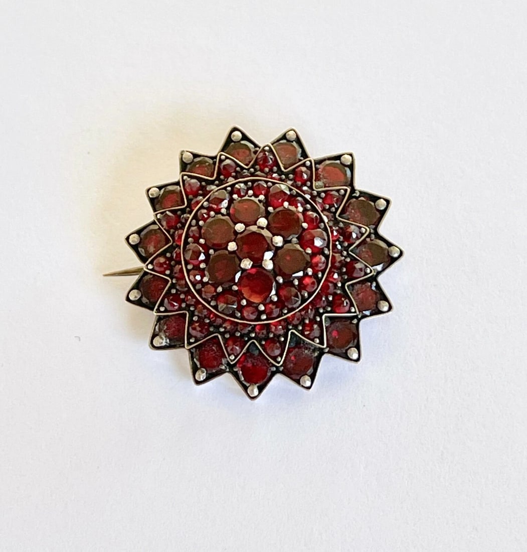 Vintage Bohemian Garnet-Style Starburst Cluster Brooch: VINTAGE BOHEMIAN GARNET-STYLE STARBURST CLUSTER BROOCH Provenance and Authenticity: This object is presented as a vintage circular brooch featuring a dense arrangement of deep red faceted stones mount