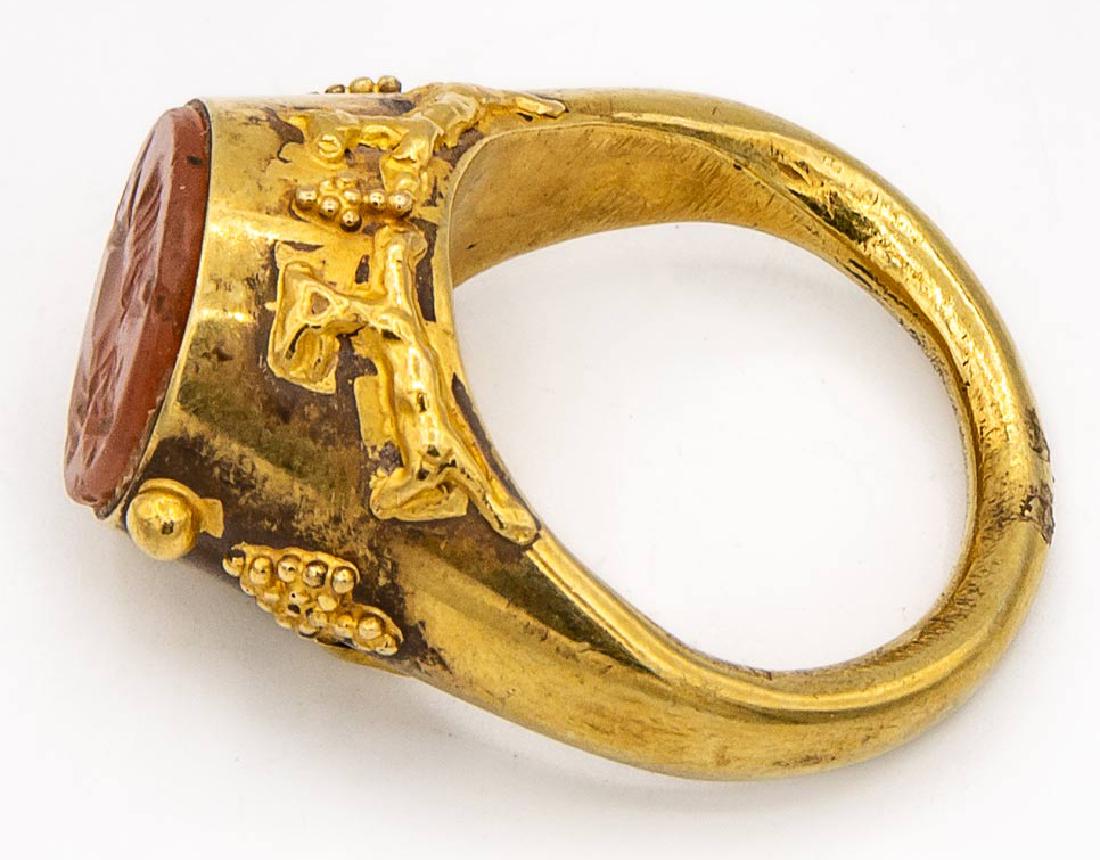 A Fine and Rare 22K Gold and Carnelian Insignia Ring,: A Fine and Rare 22K Gold and Carnelian Insignia Ring, Persia, 19th Century Description: The shoulders decorated with grapevines and rampant hares and the top set with a carnelian carved with an insign