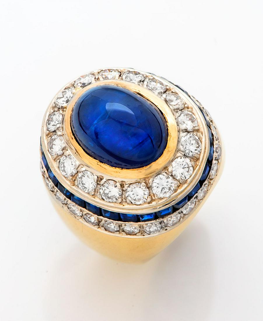 A Fine Gold Diamond and Sapphire Ring: A Fine Gold Diamond and Sapphire Ring Centered by a large, high-quality cabochon sapphire (approx. 10Ct) in a gold frame and bordered by diamonds. Mounted on a wide, thick, flared band with shoul
