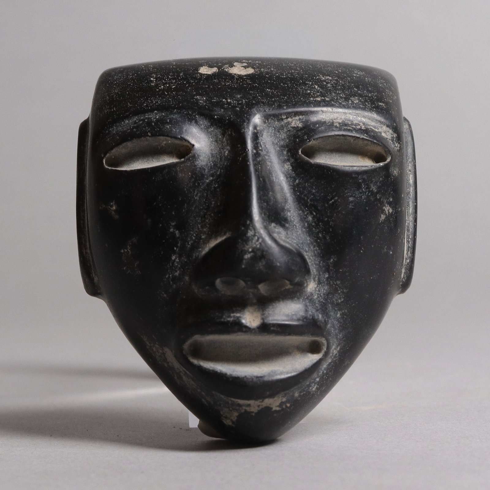 Pre-Columbian carved mask celt: Pre-Columbian carved mask celt. From a major estate. H: 3" x W: 2.65."
