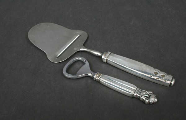 Georg Jensen Sterling Serving Pieces: Comprising: a sterling "Acorn" pattern bottle opener with a hollow handle; together with a "Mayan" (Rune) pattern sterling cheese slice, designed by Johan Rohde, each hallmarked sterling Denmark. Bott