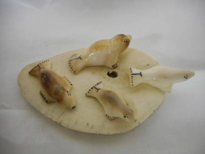 authentic alaskan carving four ivory seals artist sign: an authentic alaskan native carving four handcarved walrus ivory seals on a piece of walrus bone. this shows four seals resting on a ice flow. the coloring on the seals is gorgeous the size is 4" x 2