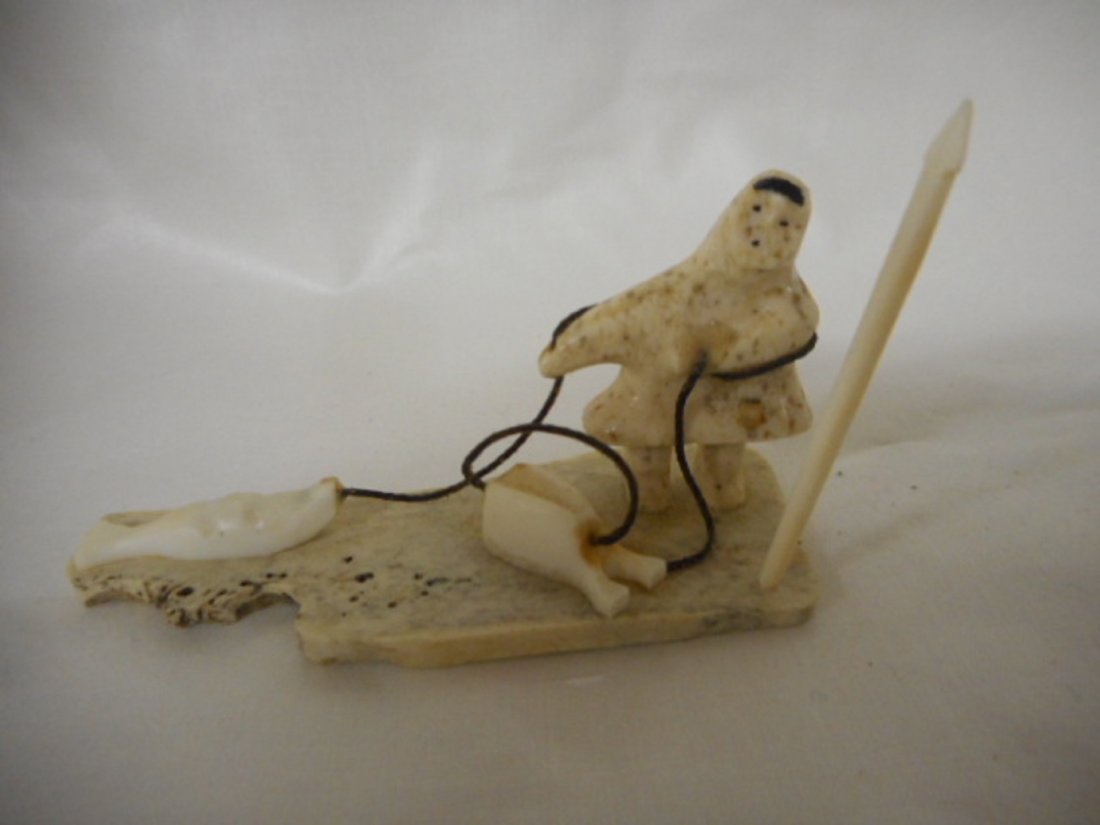 Alaskan Carving Eskimo Seal Hunter with seal artist: an authentic alaskan carving. a superb hand carved alaskan native walrus bone and walrus ivory eskimo seal hunter with a seal. this eskimo seal hunter dressed in an alaskan parka with a hood on his he
