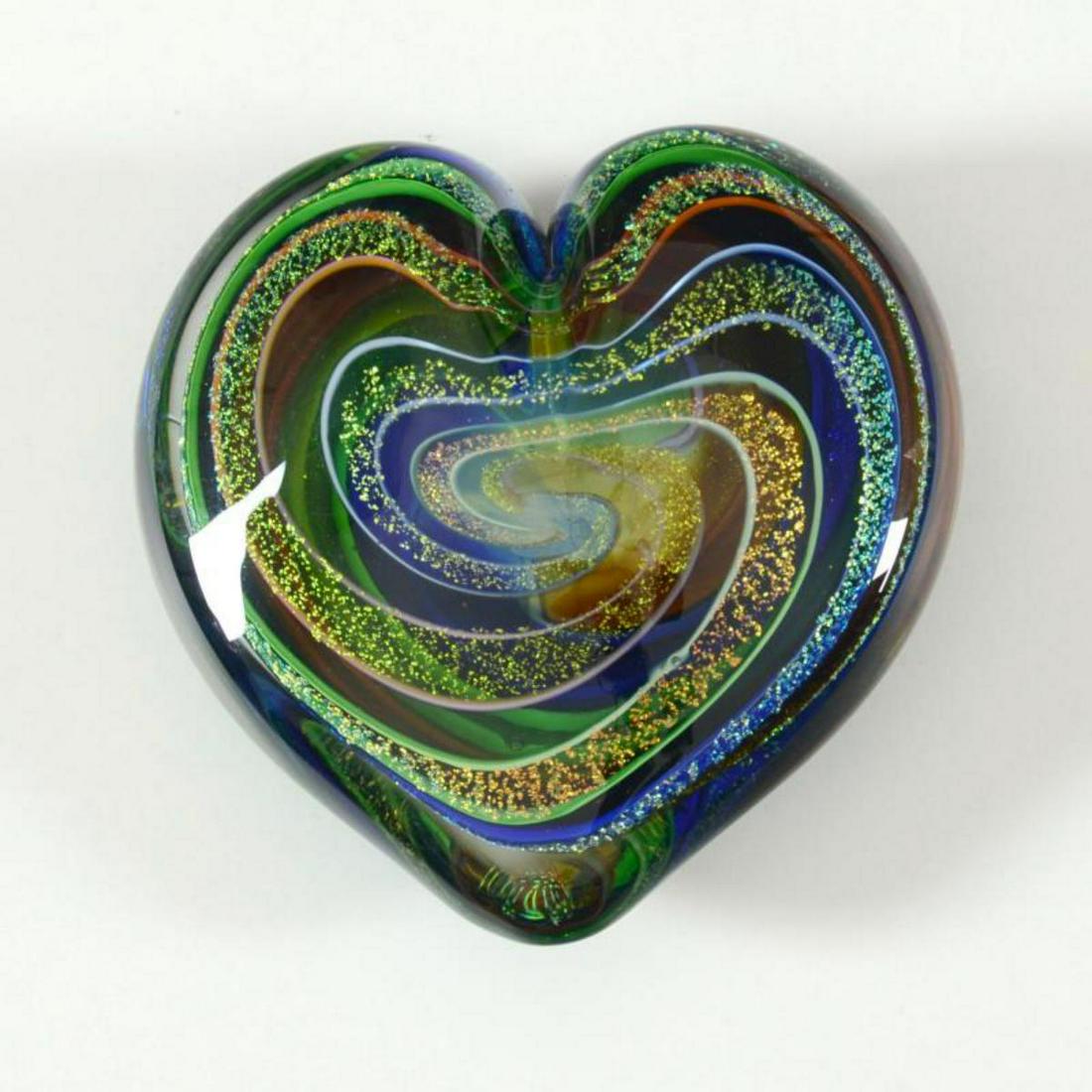 Glass Eye Studios, "Heart of Fire (Golden Rainbow)": "Heart of Fire (Golden Rainbow)" is a hand blown glass paperweight (second) from Glass Eye Studios. This piece contains ash from the 1980 volcanic eruption of Mount St. Helens. As each piece is indivi