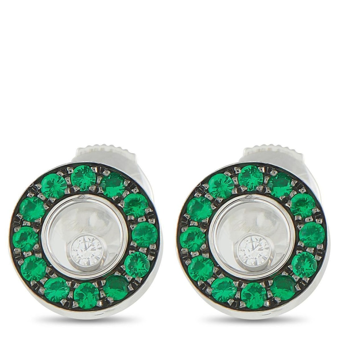 CHOPARD HAPPY DIAMONDS 18K WHITE GOLD DIAMOND AND EMERALD STUD EARRINGS: Crafted in gleaming 18K white gold, these Chopard earrings offer a beautiful contrast of dark color, vivid green, and perpetual sparkle. The design centers on a single bezel-set round diamond, set wit