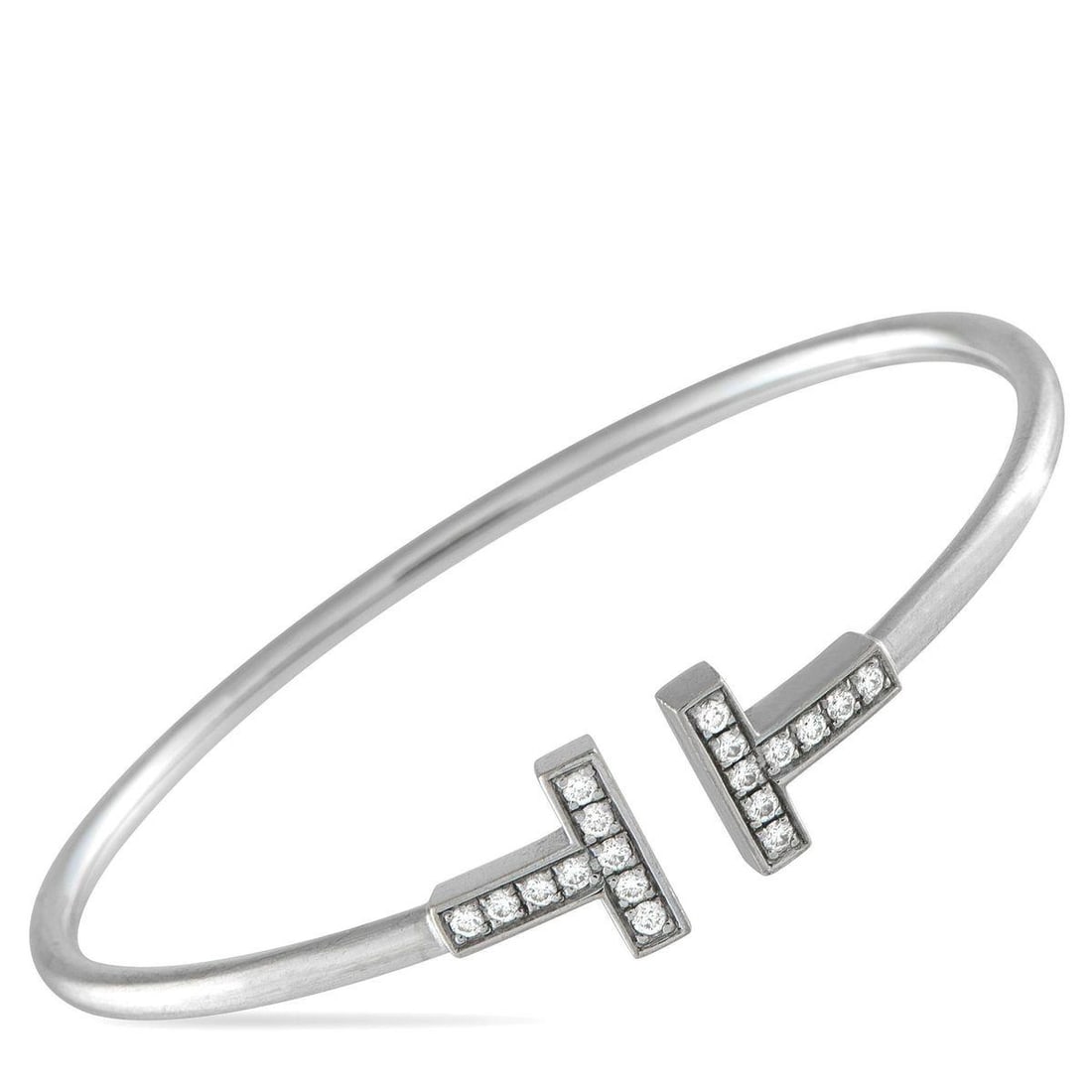 TIFFANY & CO. 18K WHITE GOLD DIAMOND T BRACELET: Modern and sophisticated, this Tiffany & Co. T Wire Bracelet pays homage to the luxury brands enduring legacy. At each end of the sleek 18K White Gold bangle, a signature T comes to life in sparkling