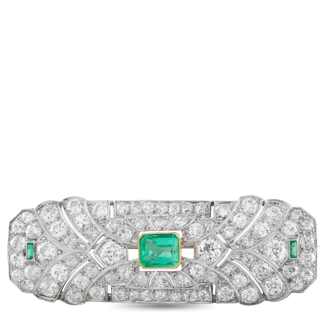PLATINUM 5.30CT DIAMOND AND EMERALD ART DECO BROOCH: Symmetry defines this Art Deco platinum brooch. At the center rests an emerald set in a yellow gold bezel, introducing a deliberate contrast. On the same horizontal line, two smaller baguette-cut emer