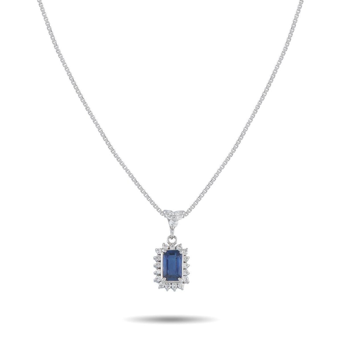 PLATINUM 0.30CT DIAMOND AND SAPPHIRE PENDANT NECKLACE: Modern. Minimal. Meticulous. A step-cut sapphire weighing 1.02 carats defines the pendant, secured by prongs set cleanly at each corner. A polished frame traces the stone's rectangular outline, sharpe