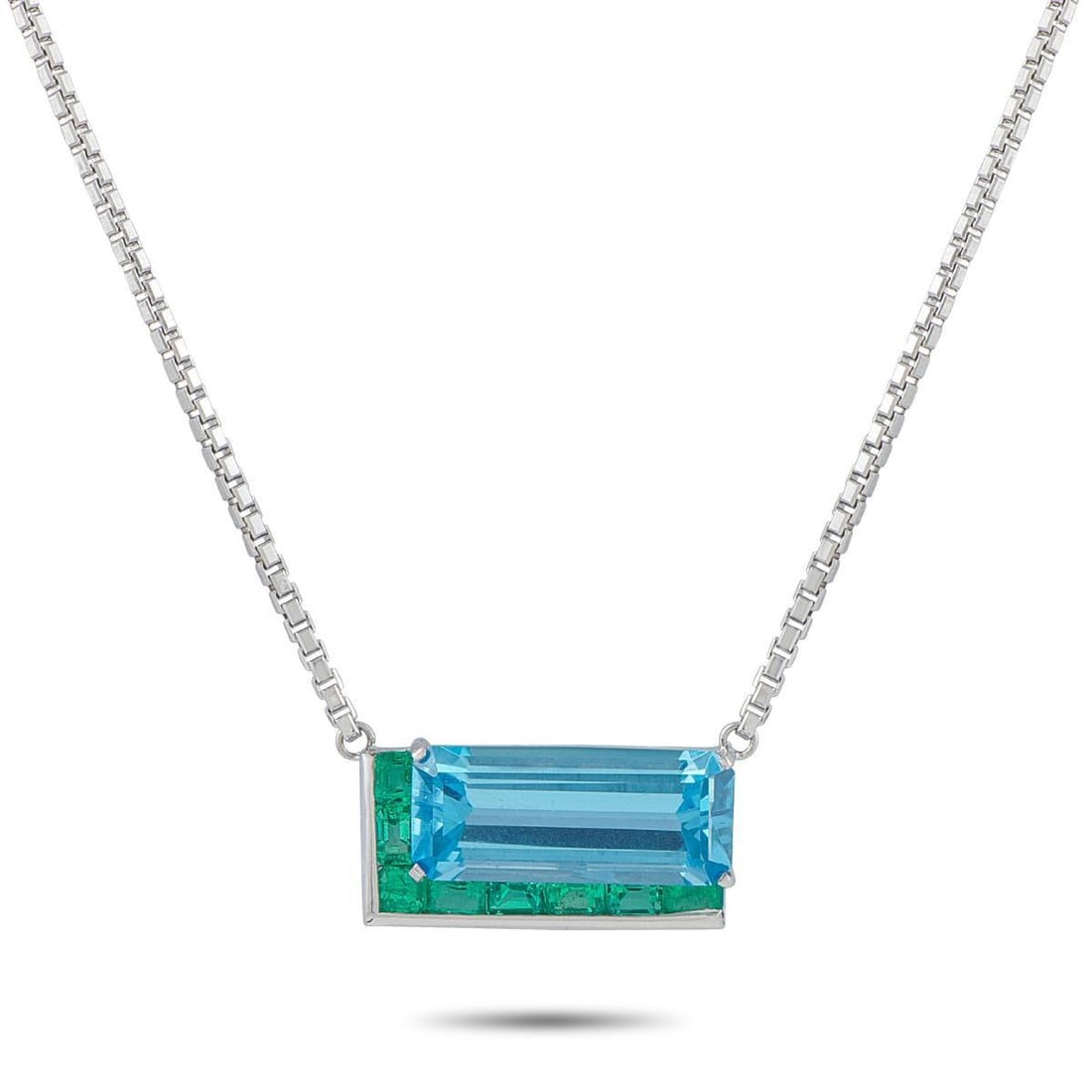 PLATINUM AND 18K WHITE GOLD 1.20CT EMERALD AND TOPAZ NECKLACE: Bold colors come together in perfect harmony on this unforgettable necklace. Crafted from a combination of Platinum and 18K White Gold, this piece features a striking pendant at the center of a 20 box