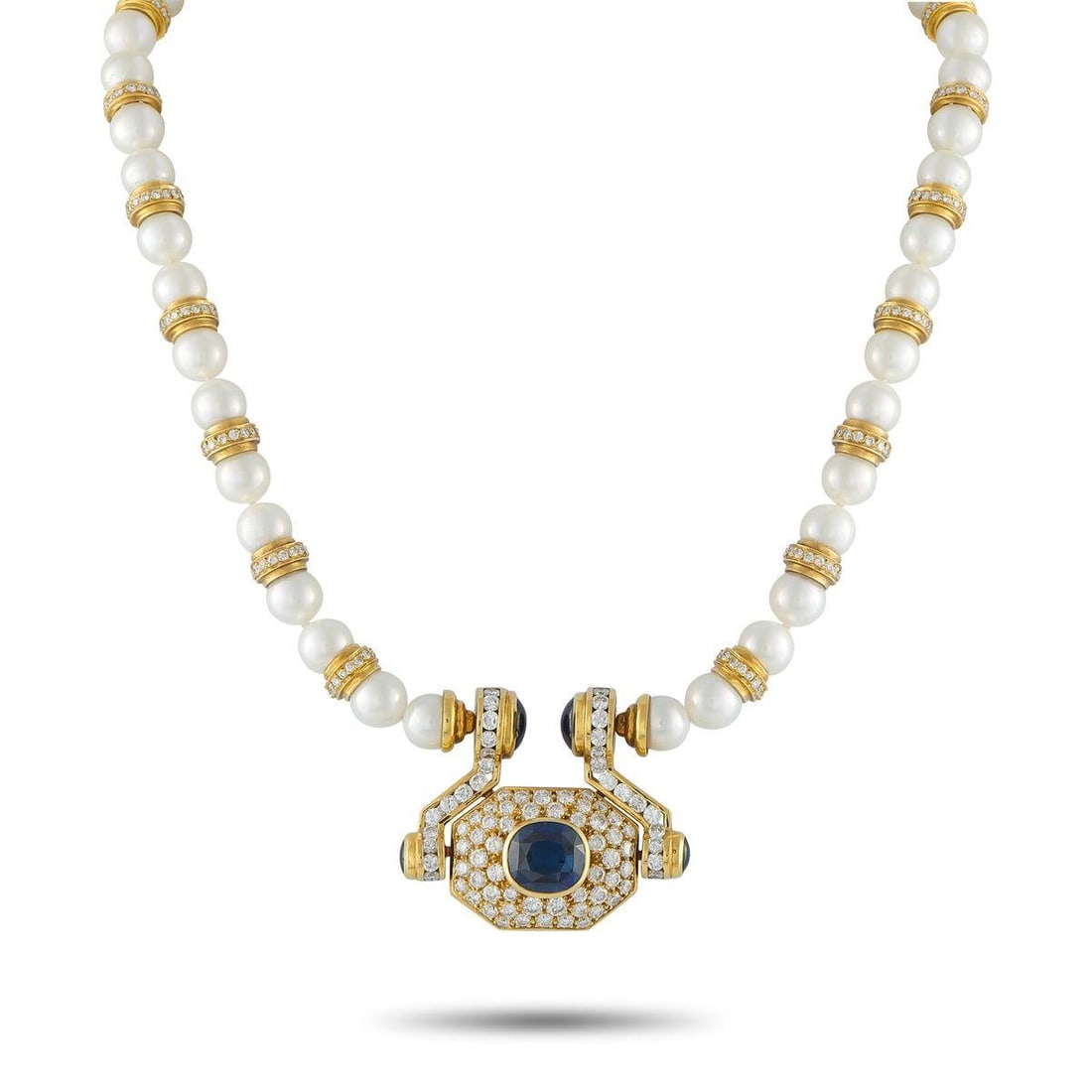18K YELLOW GOLD 7.0CT DIAMOND AND SAPPHIRE STATEMENT NECKLACE: Nothing understated here. At the center, a door knocker-inspired pendant frames a 10-carat blue sapphire, bezel-set and surrounded by diamonds across an octagonal face. Two smaller sapphires rest at t