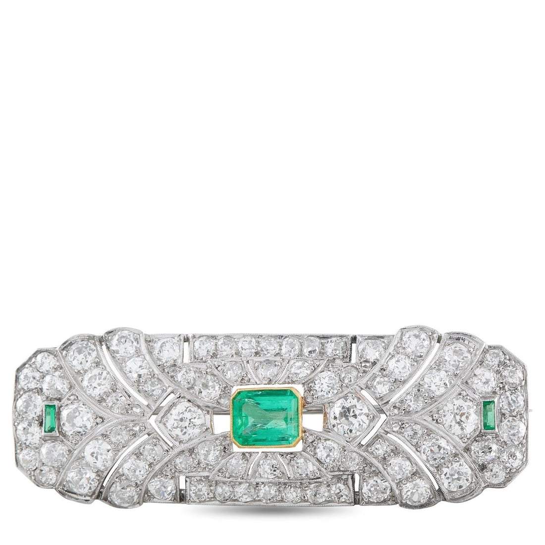 PLATINUM 5.30CT DIAMOND AND EMERALD ART DECO BROOCH: Symmetry defines this Art Deco platinum brooch. At the center rests an emerald set in a yellow gold bezel, introducing a deliberate contrast. On the same horizontal line, two smaller baguette-cut emer