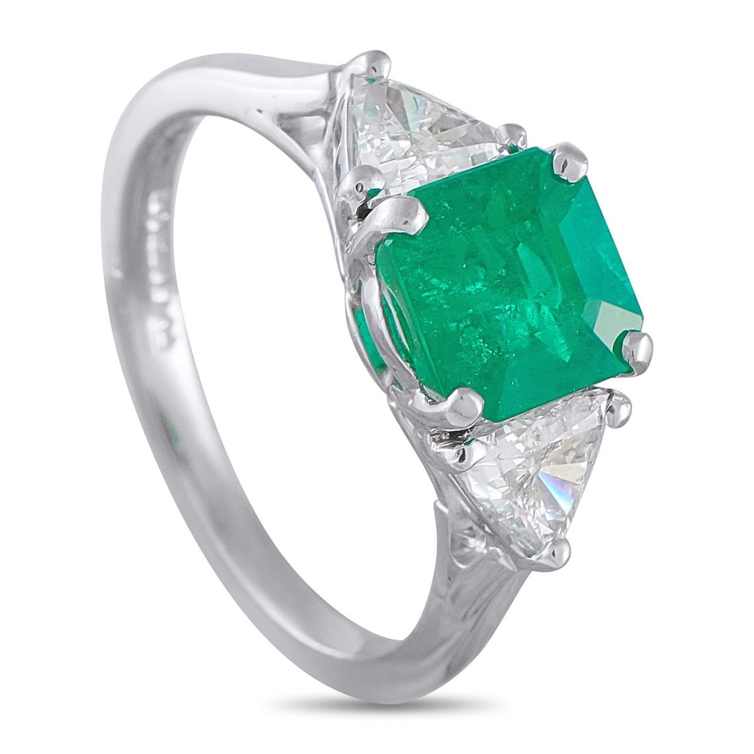 PLATINUM 0.60CT DIAMOND AND EMERALD RING: A ring built almost entirely around the pull of emerald. Fresh and cool to the eye, the 1.24-carat center stone sits right at the center with four prongs securing its corners. Trillion-cut diamonds on
