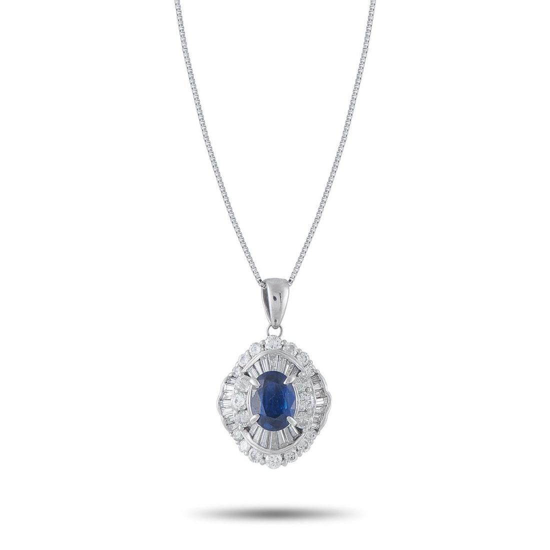 PLATINUM SAPPHIRE AND DIAMOND DOUBLE HALO PENDANT NECKLACE: A classic halo pendant in platinum, featuring a vivid oval blue sapphire at center surrounded by a double halo of baguette and round diamonds 4.05 ct total gem weight. Suspended on a 17 platinum box c