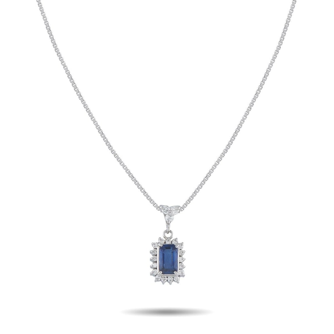 PLATINUM 0.30CT DIAMOND AND SAPPHIRE PENDANT NECKLACE: Modern. Minimal. Meticulous. A step-cut sapphire weighing 1.02 carats defines the pendant, secured by prongs set cleanly at each corner. A polished frame traces the stone's rectangular outline, sharpe