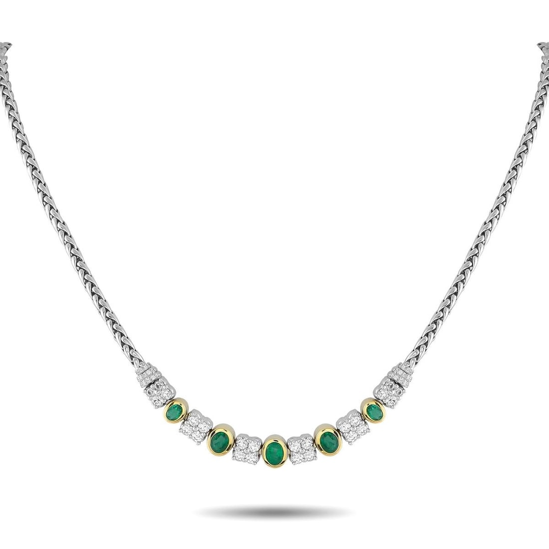 18K WHITE AND YELLOW GOLD 1.65CT DIAMOND AND EMERALD NECKLACE: An exquisite creation of style and presence. This piece features a substantial woven chain, polished in the style of a wheat braid, that lends texture and strength. At its center are tapering oval eme