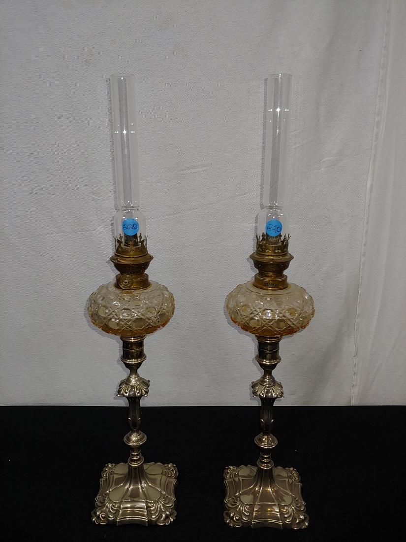 Lighting - Candlestick Lamps (2): Kerosene Lamps. Silver plated candle sticks. Lamps have clear round reservoirs w/button type design. Center draft wicks. Imprinted on wick turning knob is a Sun w/rays and letter F. On cap with R d N 