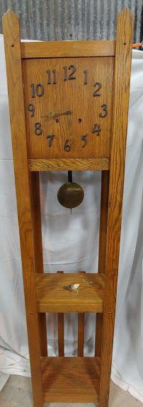 Clock - Grandfather Clock: Mission Style Grandfather Clock. Oak lathe cabinet. Face and clock workings will remove and hang like a wall clock. Raised black metal numbers. Has pendulum and key. Maker unknown.