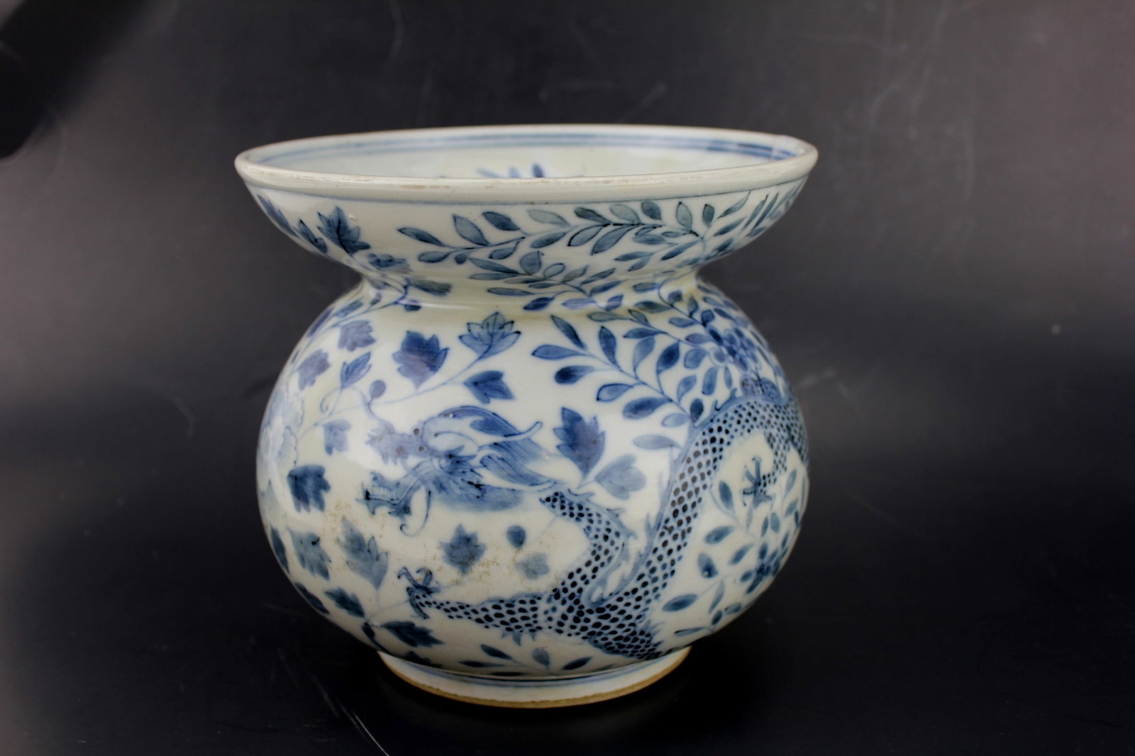 CHINESE BLUE AND WHITE SPITTOON: Decorated with dragon motifs. Size: 6 3/4 in. H. by 7 1/4 in. D.. Chip on rim. Please see pictures for detailed conditions.