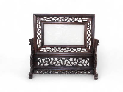 Chinese Hard Stone Table Screen: A finely carved Chinese hard stone table screen set within an elaborately pierced hardwood frame and stand. The translucent hard stone plaque depicts a pair of dragons in high relief chasing a flaming