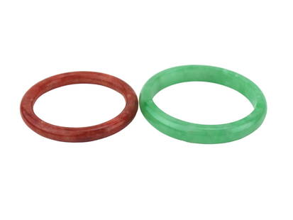 TWO JADEITE BANGLE BRACELETS: Two jadeite bangle bracelets, one in translucent apple green and one in deep mottled red, both with high-polish finishes. Approx. 2 3/4 in. and 3 in. in diameter. The green bangle shows minor internal