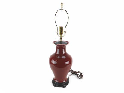 Chinese Sang de Boeuf Porcelain Vase Table Lamp: A Chinese porcelain table lamp featuring a Sang de Boeuf (oxblood) glaze with a deep, rich red finish. The vase-shaped body is mounted on a carved wooden base and fitted with modern electrical hardwar
