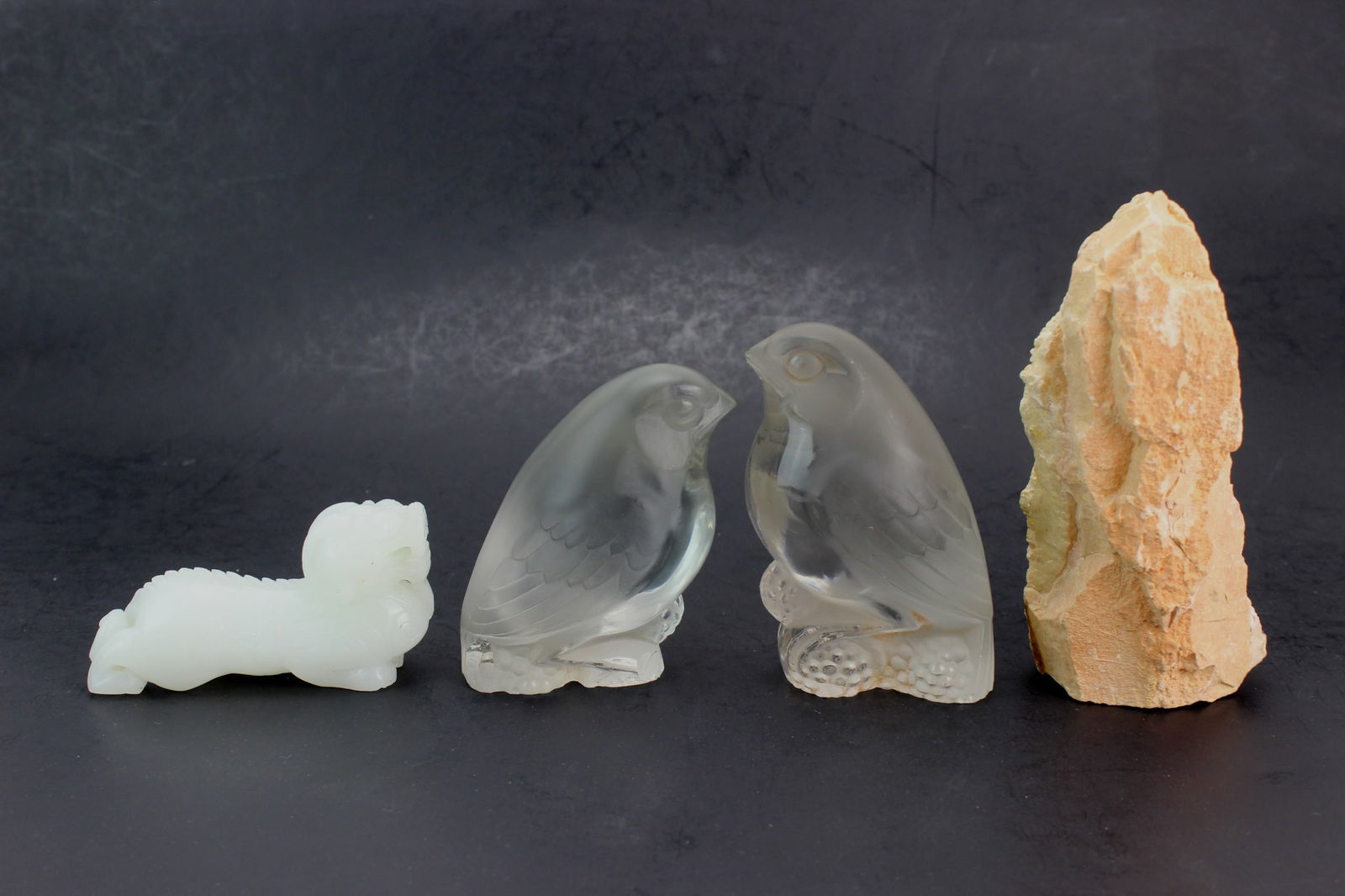Group of Stone and Glass Carvings: Set of four items including two frosted glass birds, a white stone dragon, and a natural rough stone. One bird beak with minor chips, minor wear and natural surface flaws. Sizes: Stone 5 in. (H); bird