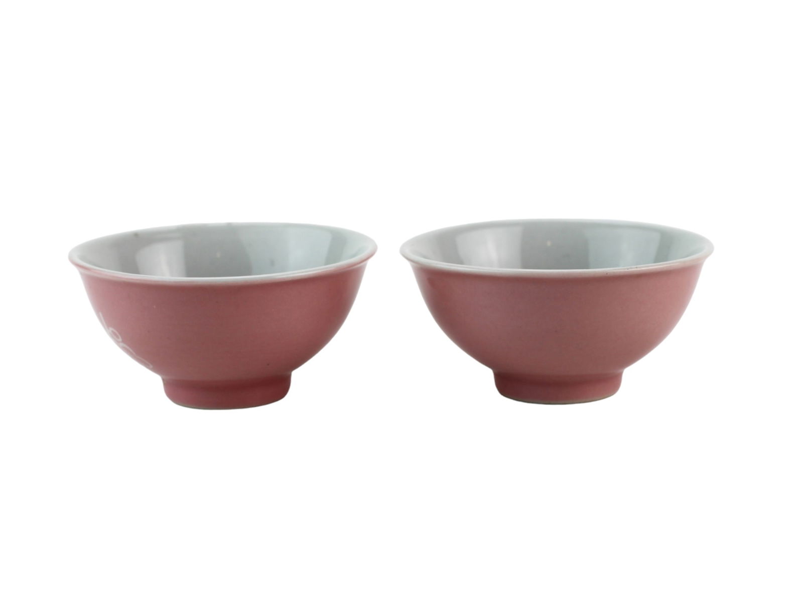 Pair of Pink Glazed Chinese Tea Bowls: Pair of Chinese porcelain tea bowls with pink exterior and celadon interior, featuring white reserve designs of birds and blossoms. Marked on base. Approx. 3 1/2 in. (D) x 1 3/4 in. (H). Minor wear an