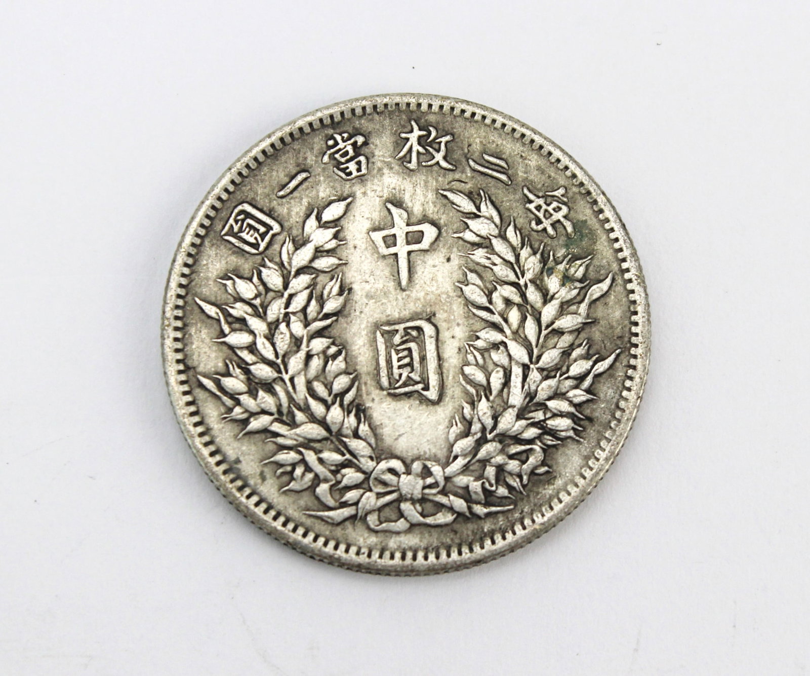 Republic of China Style Half Dollar Coin: Chinese Republic style Yuan Shikai coin with wreath reverse, showing moderate wear, surface marks, and light toning. Approx. 13.5 g, 31.8 mm diameter, 2.1 mm thick. AUTHENTICITY NOT GUARANTEED; ITEMS 