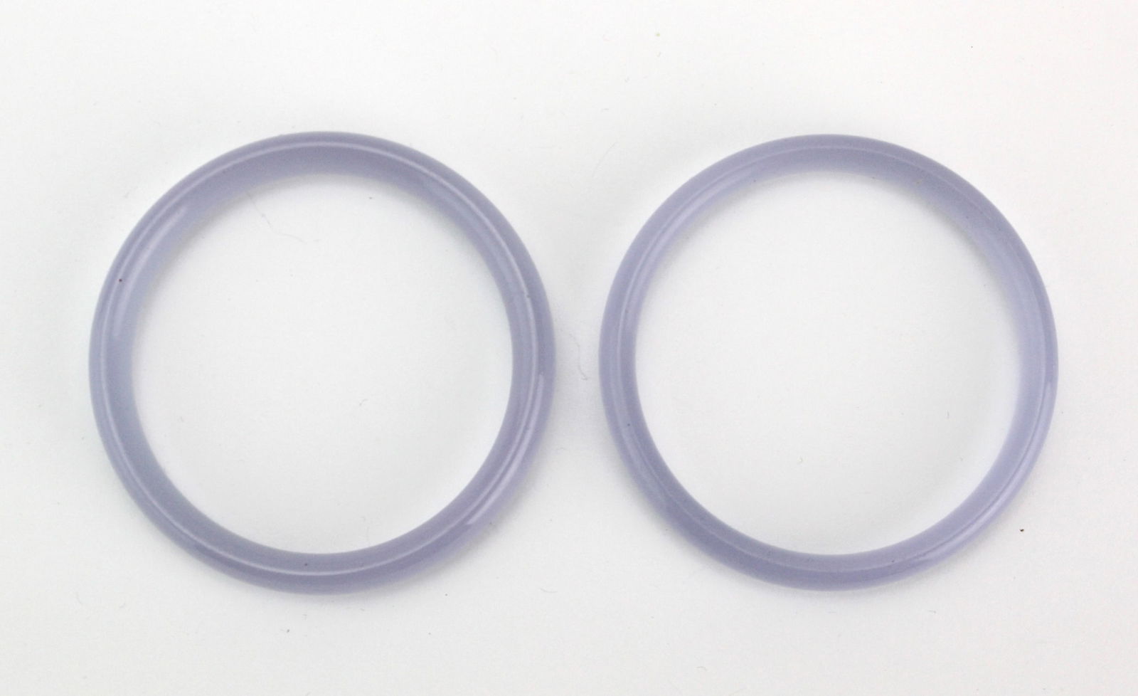 Pair of Lavender Hardstone Bangles: A pair of translucent lavender hardstone bangles with smooth polish and natural color variations, both in good condition. Approx. 68.5 mm (outer) × 56 mm (inner) diameter.