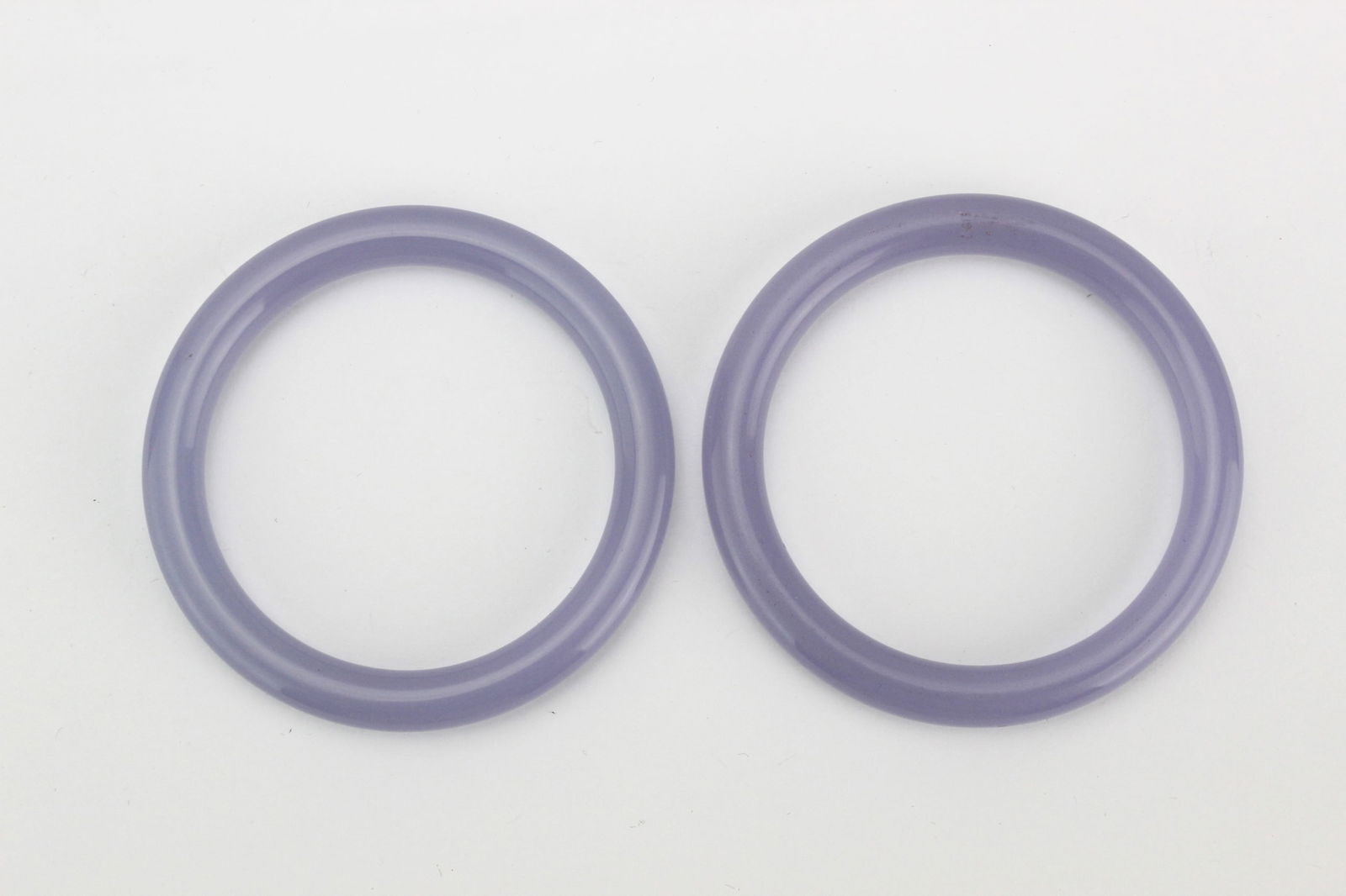 Pair of Lavender Hardstone Bangles: A pair of translucent lavender hardstone bangles with smooth polish; one has minor surface marks, both in good condition. Approx. 72.5 mm (outer) × 57 mm (inner) diameter.