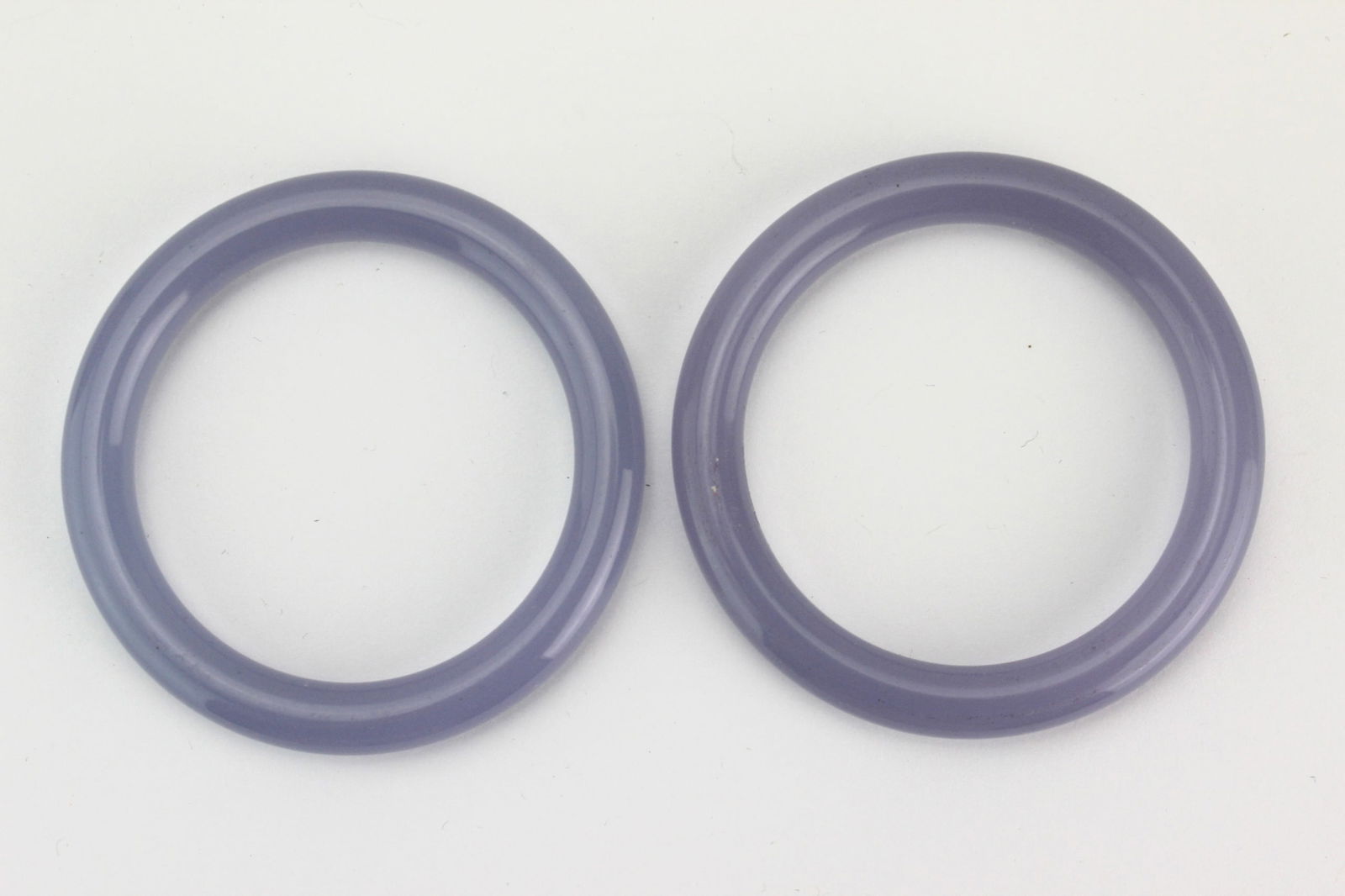Pair of Lavender Hardstone Bangles: A pair of lavender hardstone bangles with smooth polished surface, natural inclusions, and light wear. Approx. 72.0 mm (outer) × 54.4 mm (inner) diameter.