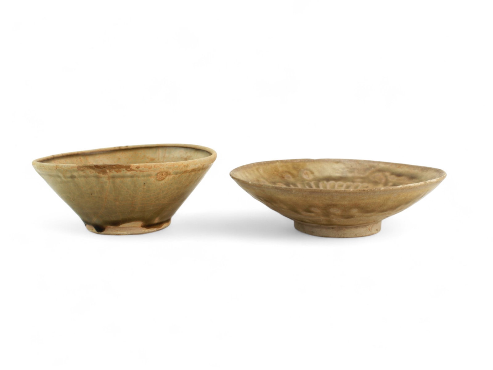 Two Chinese Glazed Bowls with Carved Floral Motif: A pair of Chinese porcelain bowls, one light olive with impressed foliate design and one darker with floral pattern. Both show glaze crackling, chips, and rim wear consistent with age and use. Sizes a