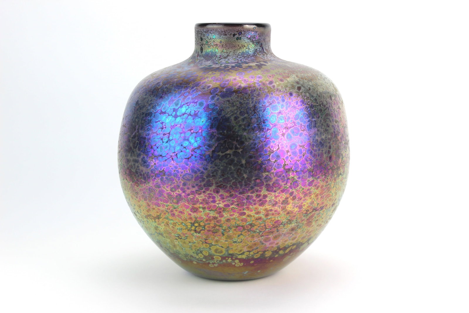 Signed Studio Art Glass Vase, Iridescent Finish: Studio art glass vase by Dan Truel, dated 1991, featuring a rounded ovoid form with narrow neck and vivid iridescent finish in purples, blues, and golds with a mottled bubble pattern. Approx. 9 × 8 1
