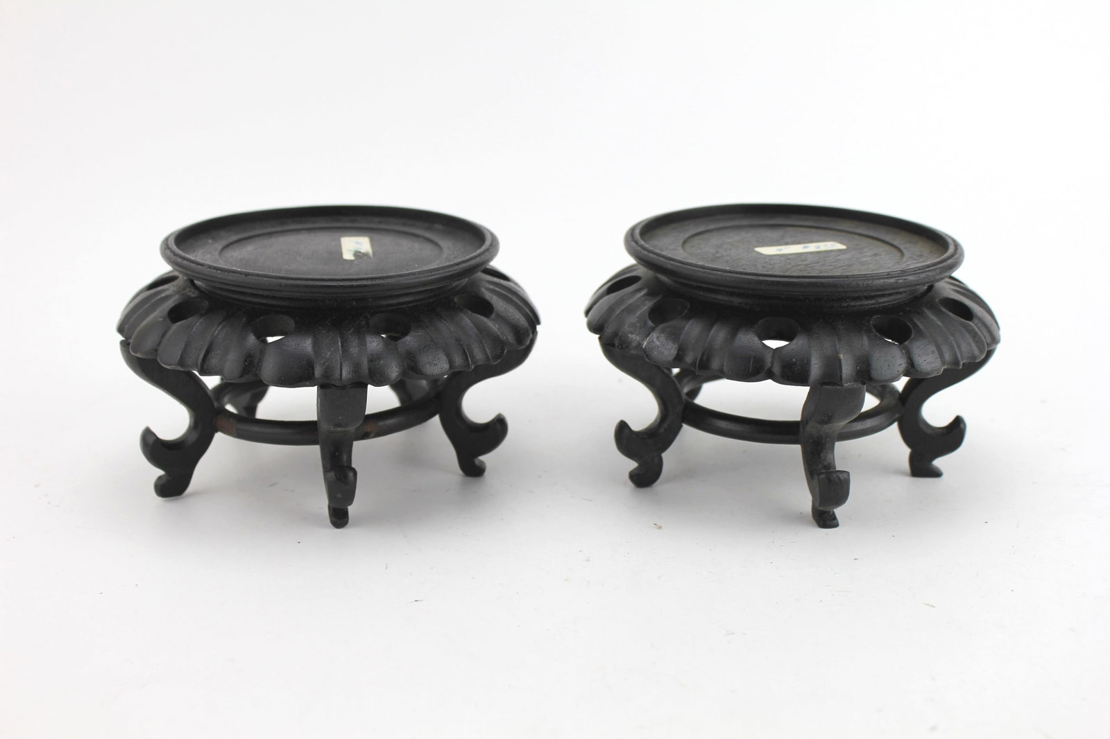 Pair of Carved Wood Stands with Pierced Rims: A pair of finely carved round wood stands featuring pierced lotus petal-style rims and curved legs. Each stand measures approximately 5 1/2 inches in diameter and 3 1/4 inches in height.
