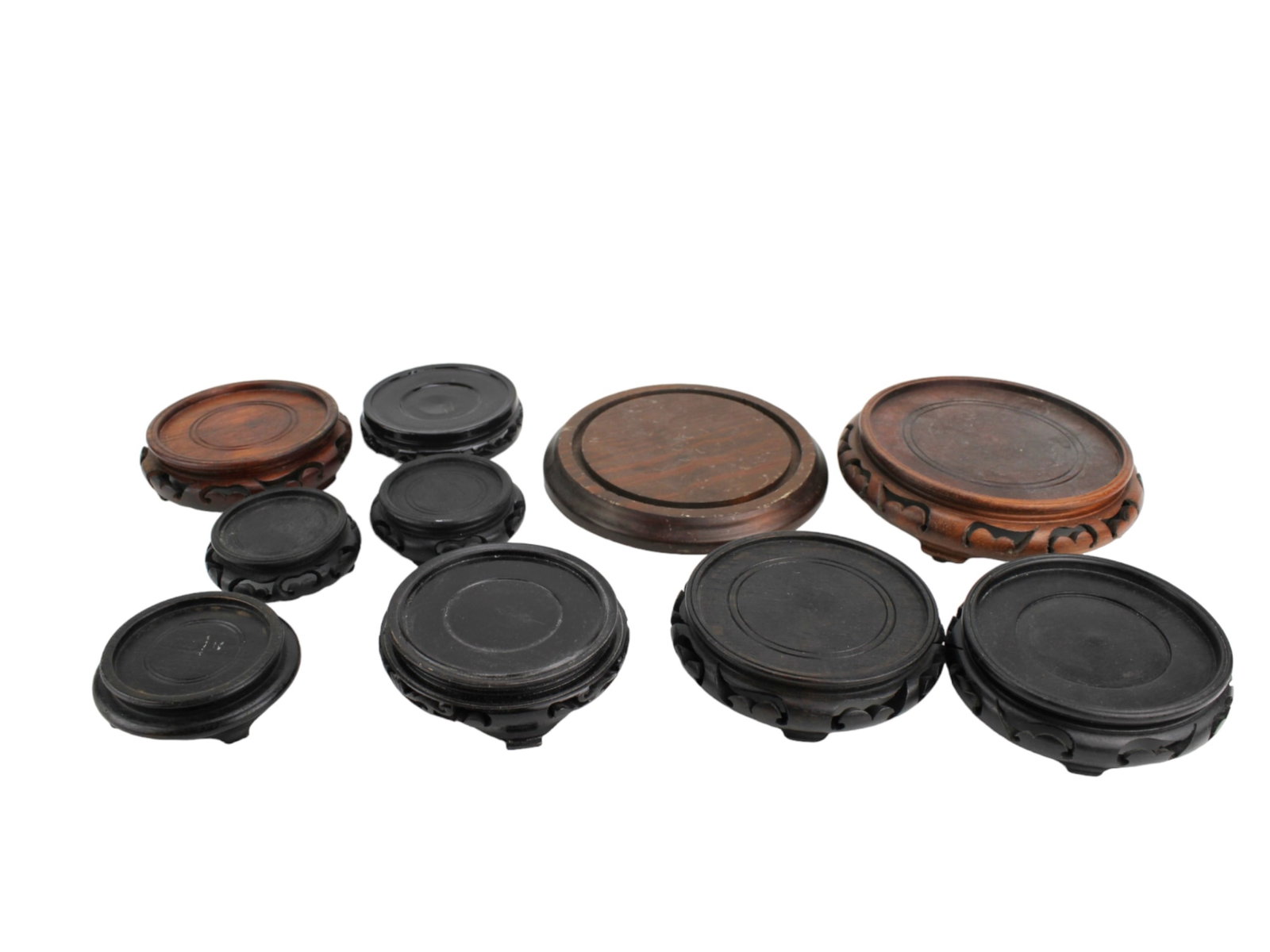 Group of 10 Chinese Carved Wood Stands: Collection of ten Chinese hardwood stands, variously carved with pierced aprons and smooth tops. Largest approx. 7 1/2 in. (D) x 1 3/4 in. (H). Show signs of use with chips, scratches, and old repairs