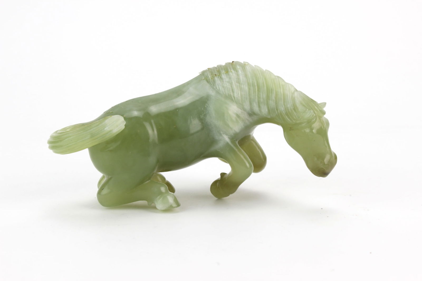 Carved Chinese Serpentine Jade Horse Figurine: A finely carved serpentine jade horse figurine in dynamic pose, showing translucent stone with natural inclusions and tonal variations. Approx. 4 1/2 in. (L) × 2 in. (W) × 2 1/2 in. (H). Condition: