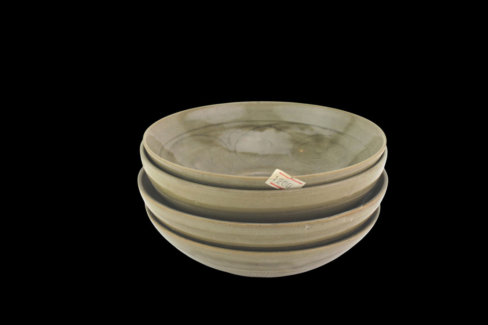 Four Chinese Celadon Bowls with Leaf Design: Set of four Chinese celadon-glazed bowls, each Approx. 6 3/4 in. Diam. by 2 1/2 in. H.. Features carved leaf or swirl motifs under olive-toned glaze. Each with neatly incised base lines. Minor glaze