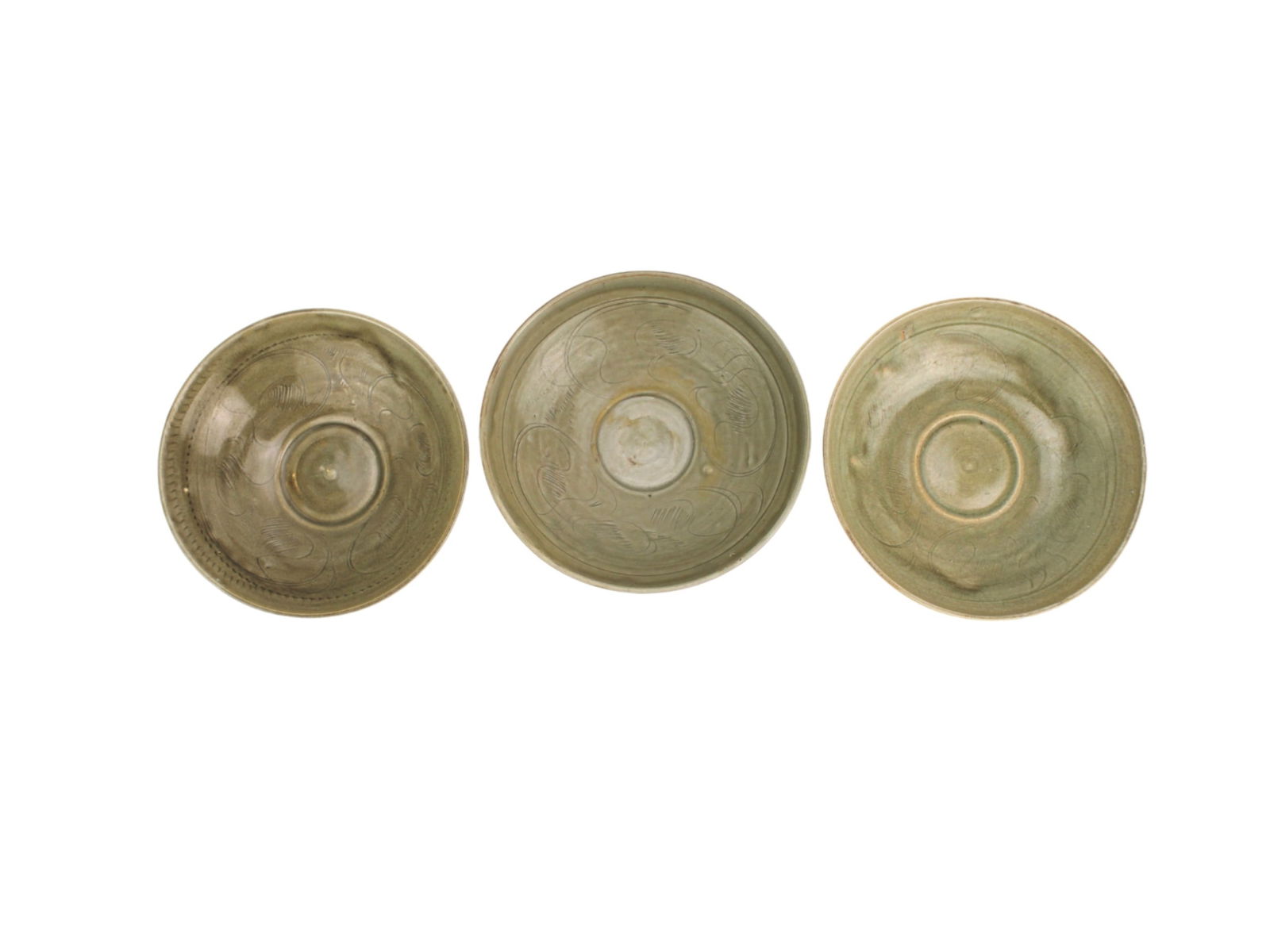 Three Chinese Celadon Incised Bowls: Set of three Chinese celadon glazed bowls, each measuring approximately 6 3/4 inches in diameter. The interiors feature incised abstract or floral patterns under a light olive-green glaze. Some