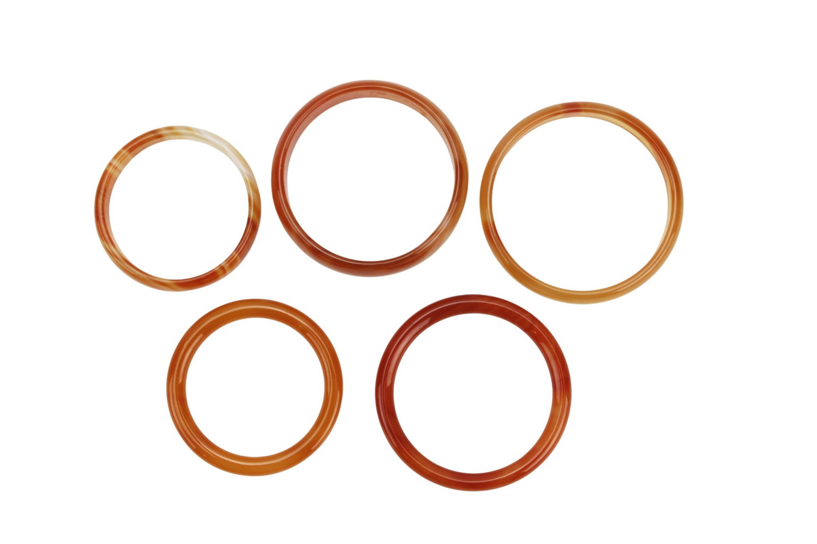 Five Assorted Hardstone Bangles: Five Assorted Hardstone Bangles. Polished in warm amber and reddish tones. Largest approx. 60 mm outer × 52.3 mm inner diameter. Good condition with light wear and natural inclusions.