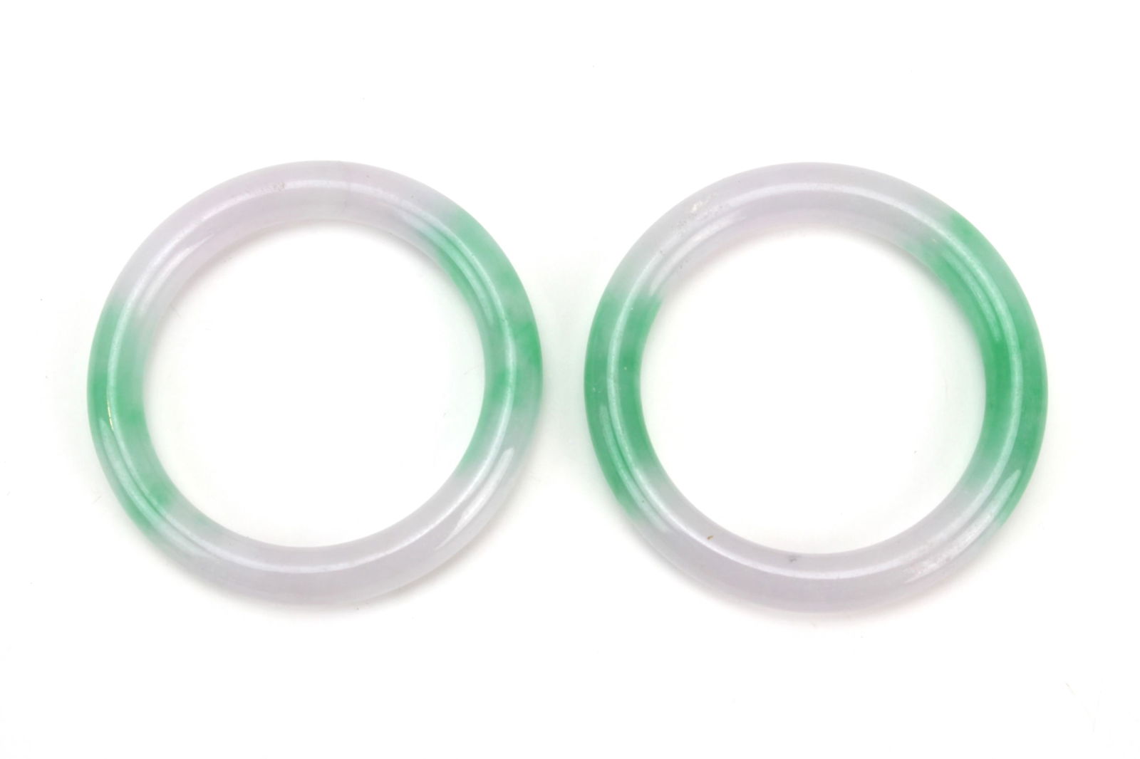 Pair Green & Lavender Jadeite Rings: A pair of jadeite rings with soft green and pale lavender tones, showing smooth polish and natural translucency. Largest ring measures approx. 54 mm (outer) X 40 mm (inner) diameter. Condition is
