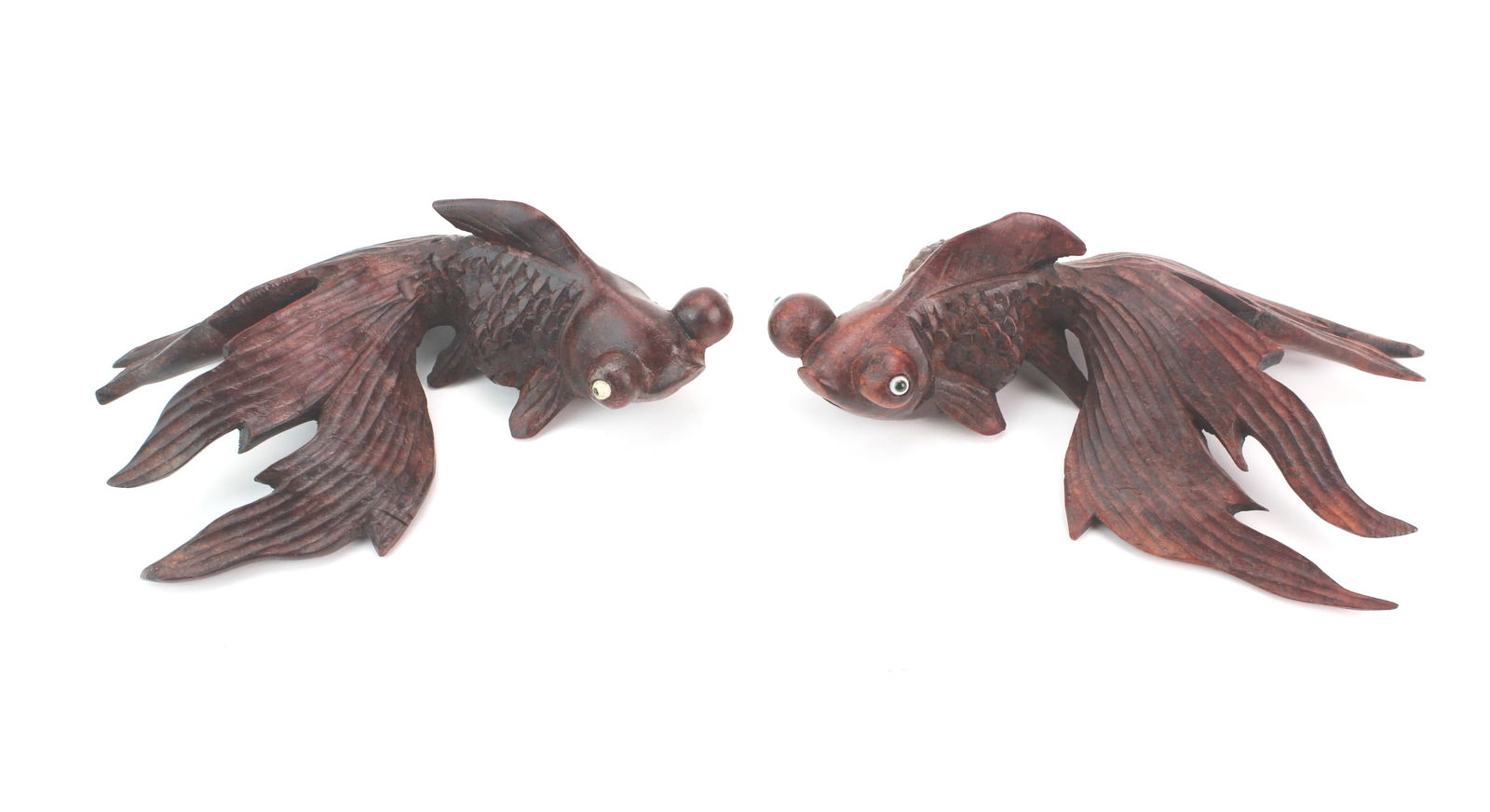 Pair of Carved Wood Goldfish Figures: Pair of finely carved wooden goldfish with textured scales, flowing fins, and inlaid eyes. Rich dark-brown finish with minor wear and light scratches. Each approx. 6¼ X 4½ X 2 in.