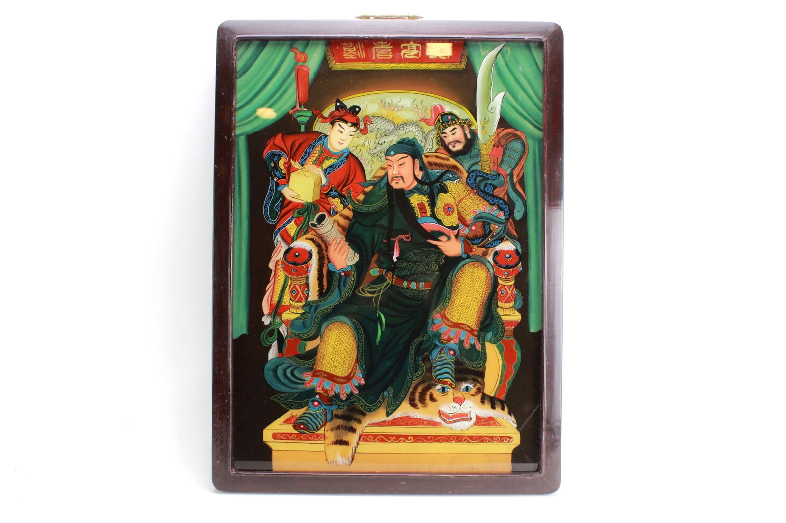 Chinese Reverse Glass Painting of Guan Yu: Chinese reverse glass painting featuring Guan Yu seated on a tiger-skin throne with two attendants. Vivid colors and traditional motifs symbolize strength and loyalty, all set in a dark wooden frame.