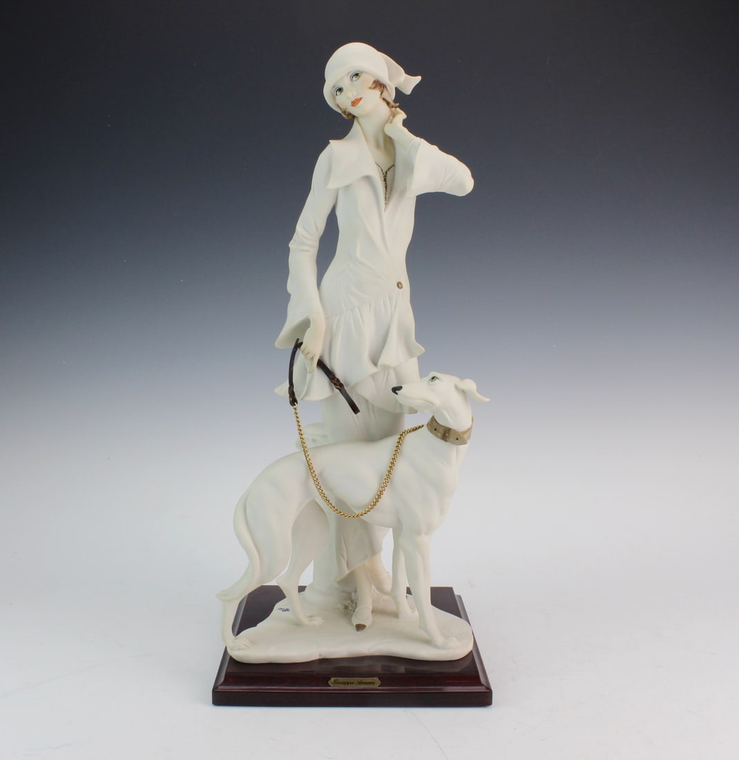 Armani Lady with Greyhound Figurine: Elegant 1992 Giuseppe Armani Florence figurine depicting a stylish lady with her greyhound. Measures 16 in. (H) X 7 in. (W) X 7 in. (L) including base. Features finely sculpted details, gold-tone