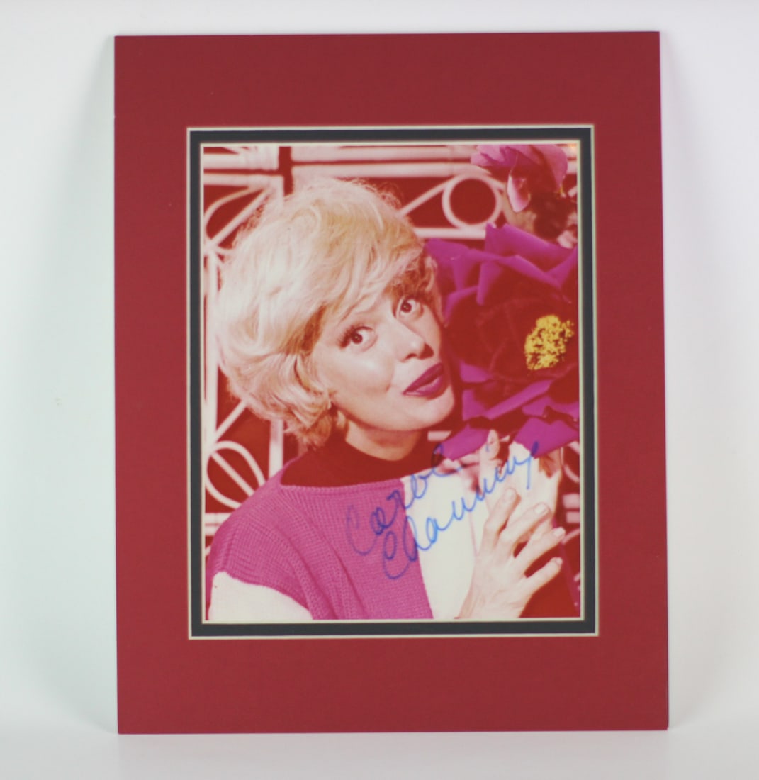 Carol Channing Signed Color Photo: Color 8 × 10 in. photo of Carol Channing holding a large flower, hand-signed in blue ink. Matted to approx. 11 × 14 in. Includes Certificate of Authenticity. Very good condition with a clear